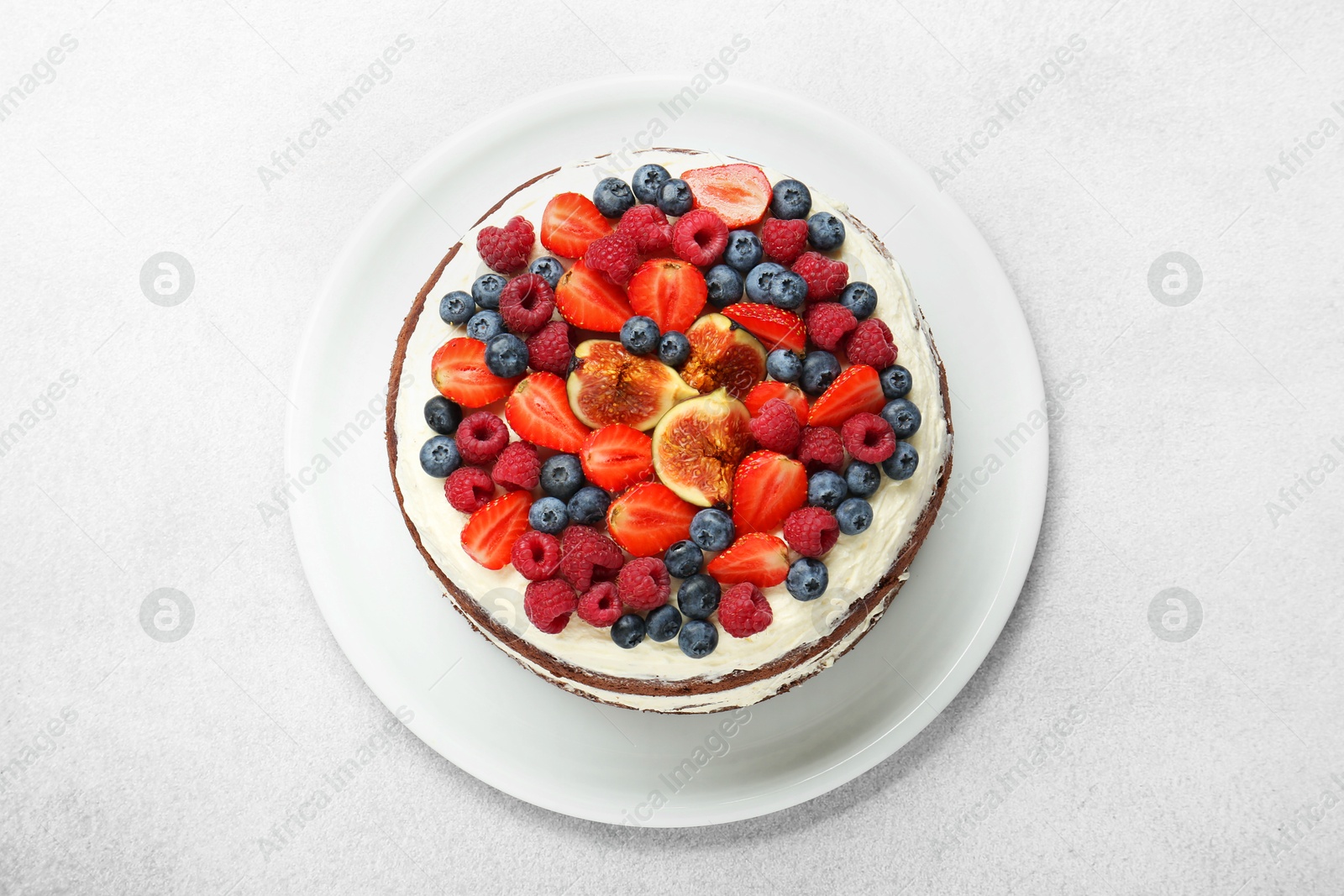 Photo of Delicious chocolate sponge cake with berries on light table, top view