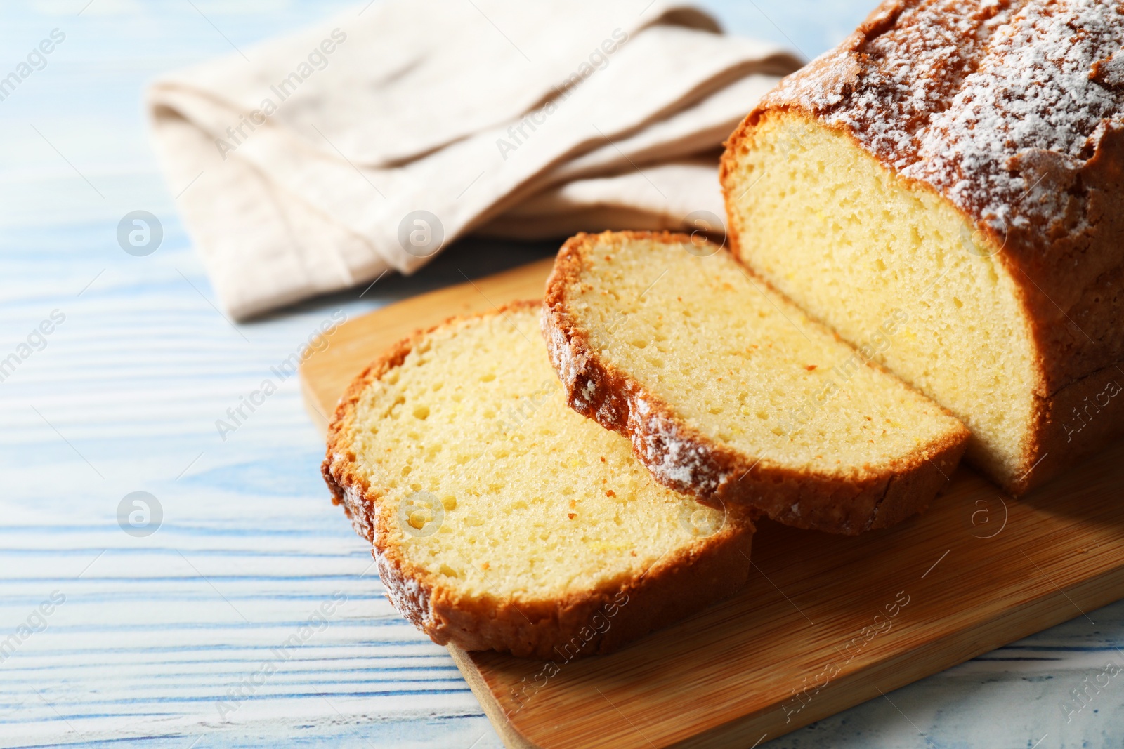 Photo of Freshly baked sponge cake on light blue wooden table, closeup