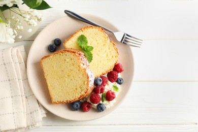 Photo of Freshly baked sponge cake, whipped cream, berries and mint on white wooden table, top view. Space for text