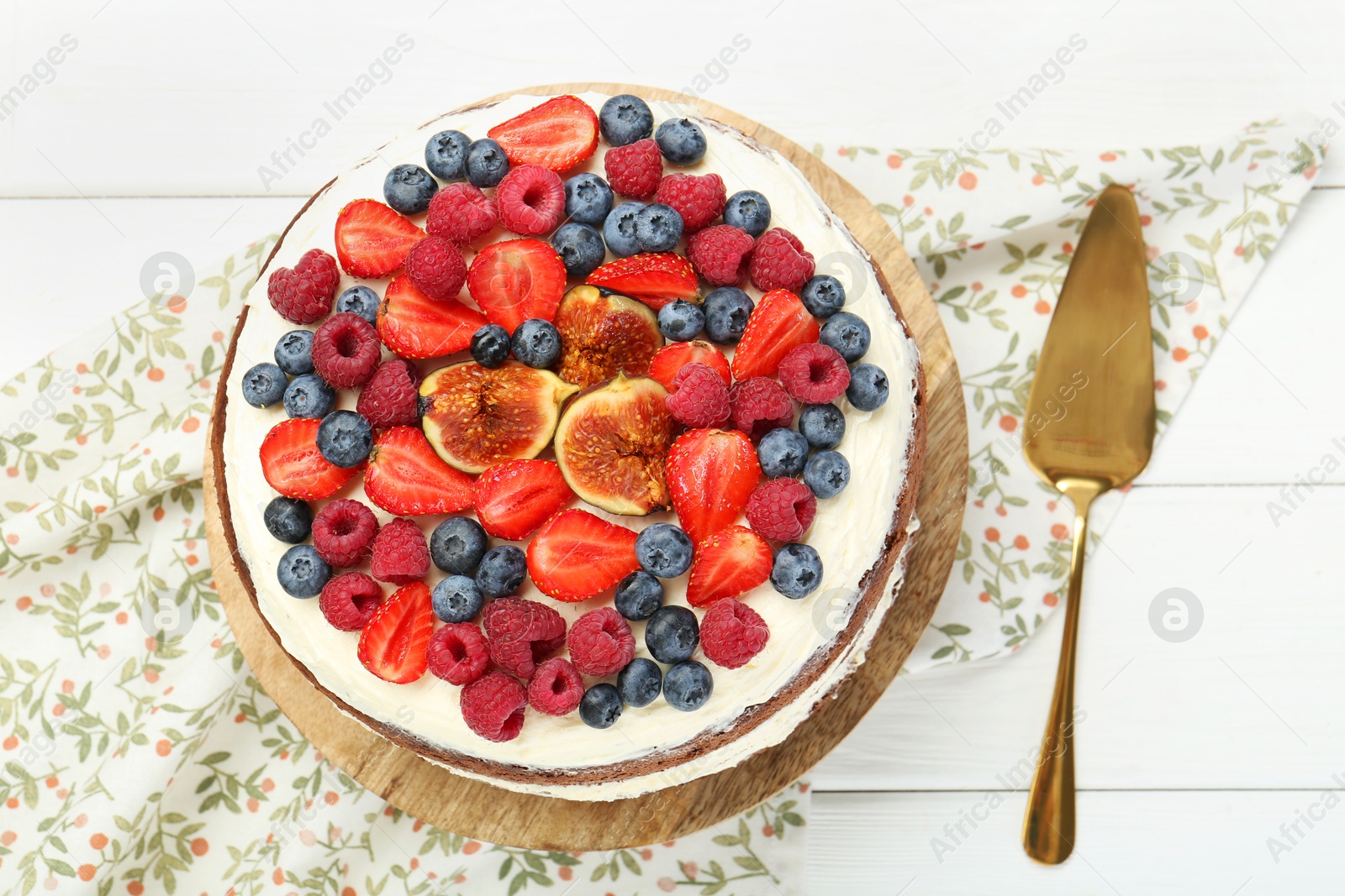 Photo of Delicious chocolate sponge cake with berries and server on white wooden table, top view