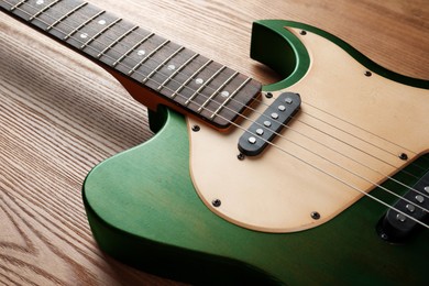 Image of Green electric guitar on wooden background, closeup. Musical instrument