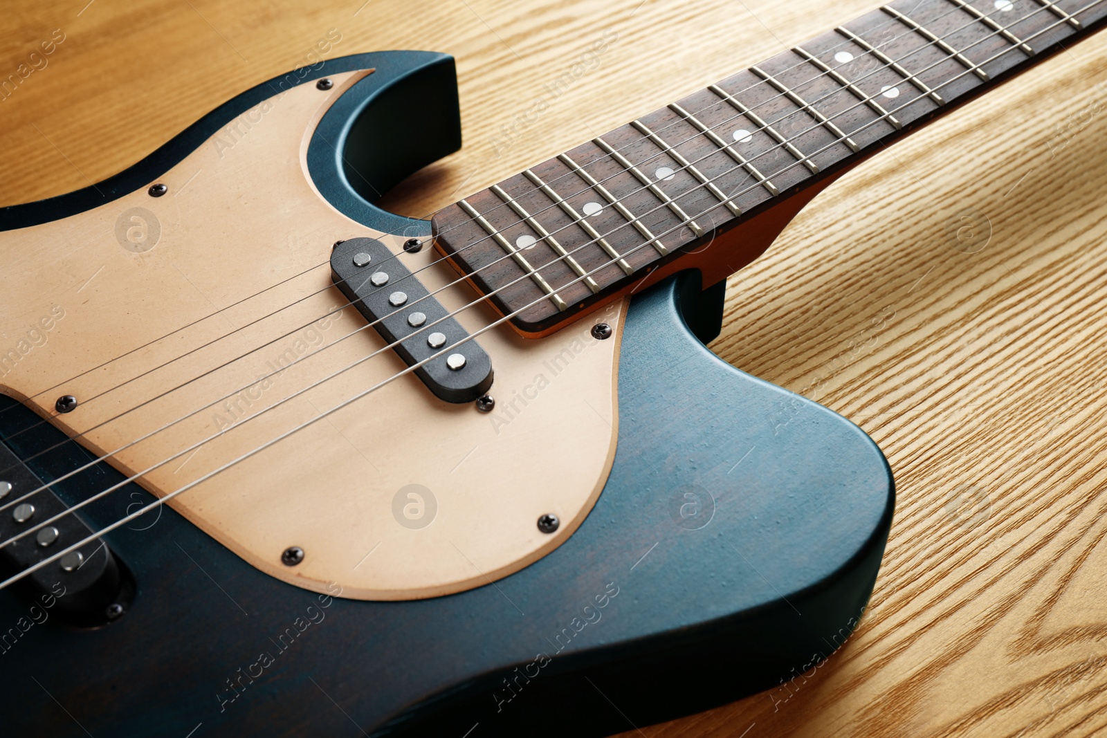 Image of Blue electric guitar on wooden background, closeup. Musical instrument