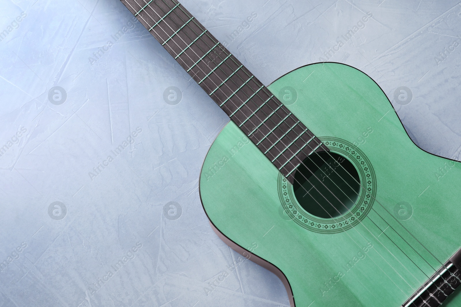 Image of Green acoustic guitar on light blue background, top view. Musical instrument