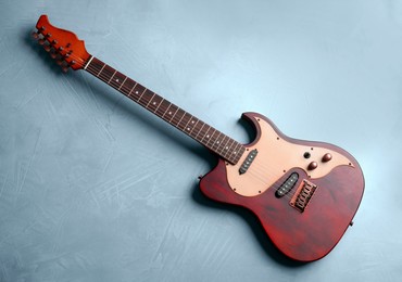 Image of Red electric guitar on light blue background, top view. Musical instrument