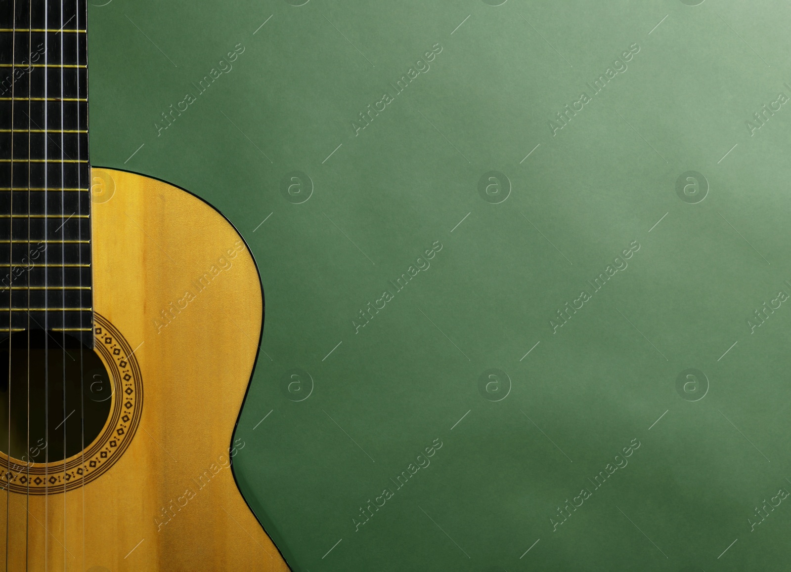 Image of Acoustic guitar on green background, top view. Musical instrument