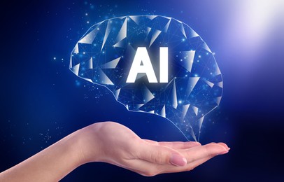 Image of Artificial intelligence. Woman holding virtual brain with AI abbreviation on dark blue background, closeup