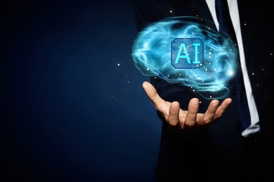 Image of Artificial intelligence. Businessman holding virtual brain with AI abbreviation on dark blue background, closeup. Space for text