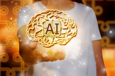 Image of Artificial intelligence. Woman holding virtual brain with AI abbreviation, closeup. Puzzle pieces on background