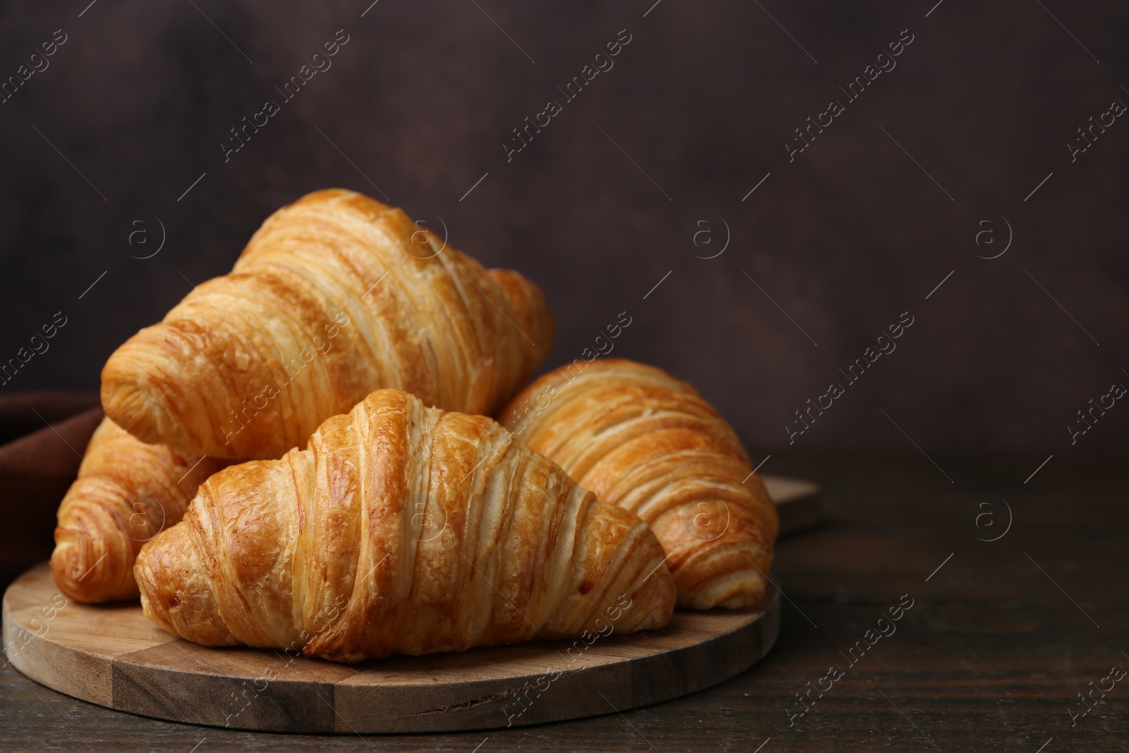 Photo of Tasty fresh croissants on wooden table, closeup. Space for text