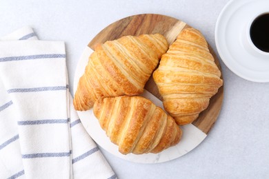 Photo of Tasty fresh croissants and cup of coffee on light grey table, flat lay