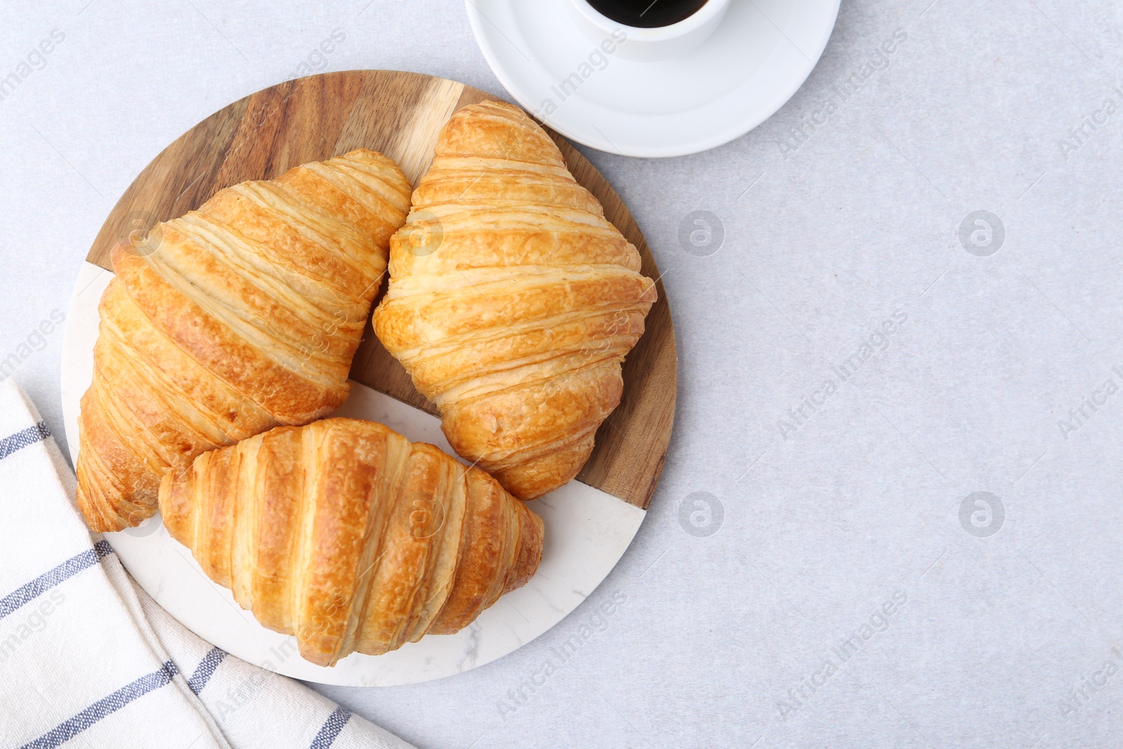 Photo of Tasty fresh croissants and cup of coffee on light grey table, flat lay. Space for text