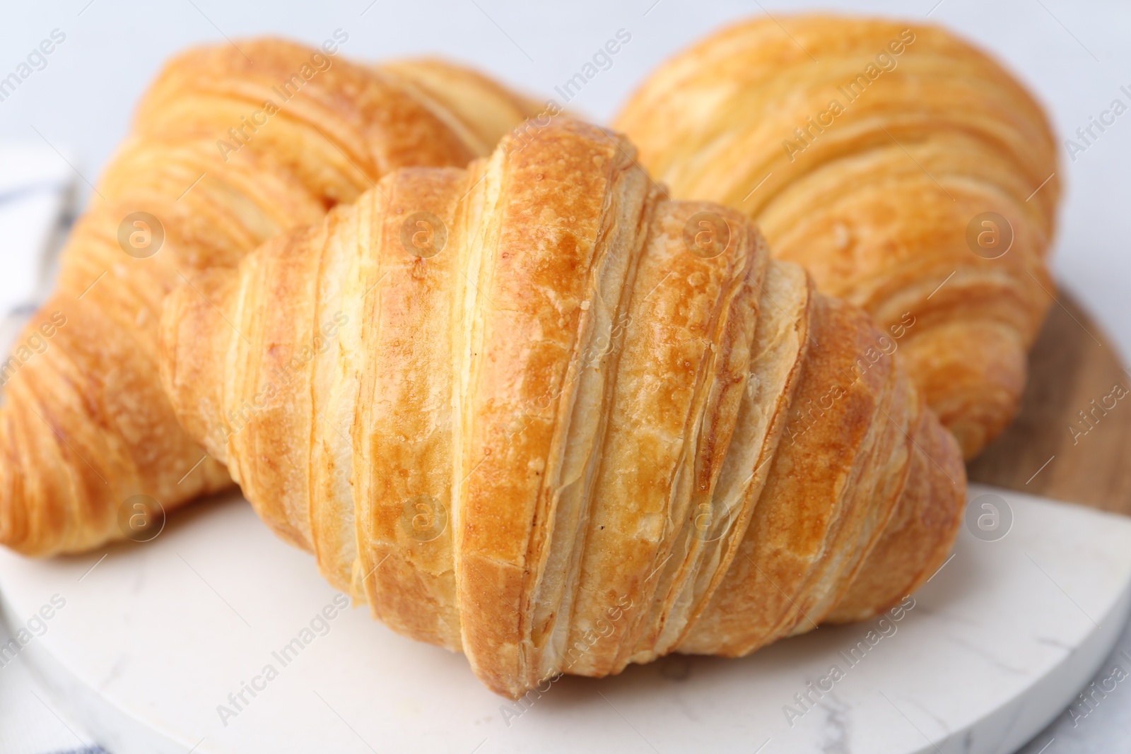 Photo of Tasty fresh croissants on light table, closeup