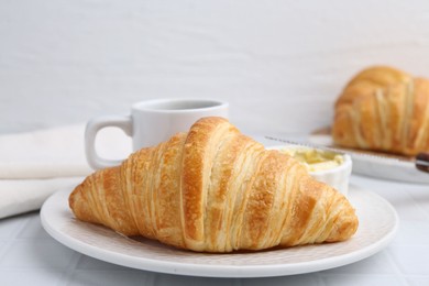 Photo of Tasty fresh croissant served on white tiled table, closeup