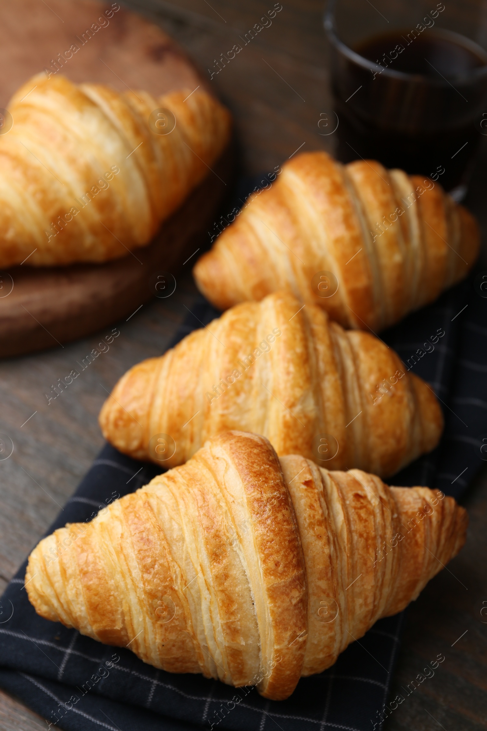 Photo of Tasty fresh croissants on wooden table, closeup. Puff pastry