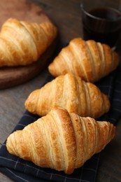 Photo of Tasty fresh croissants on wooden table, closeup. Puff pastry