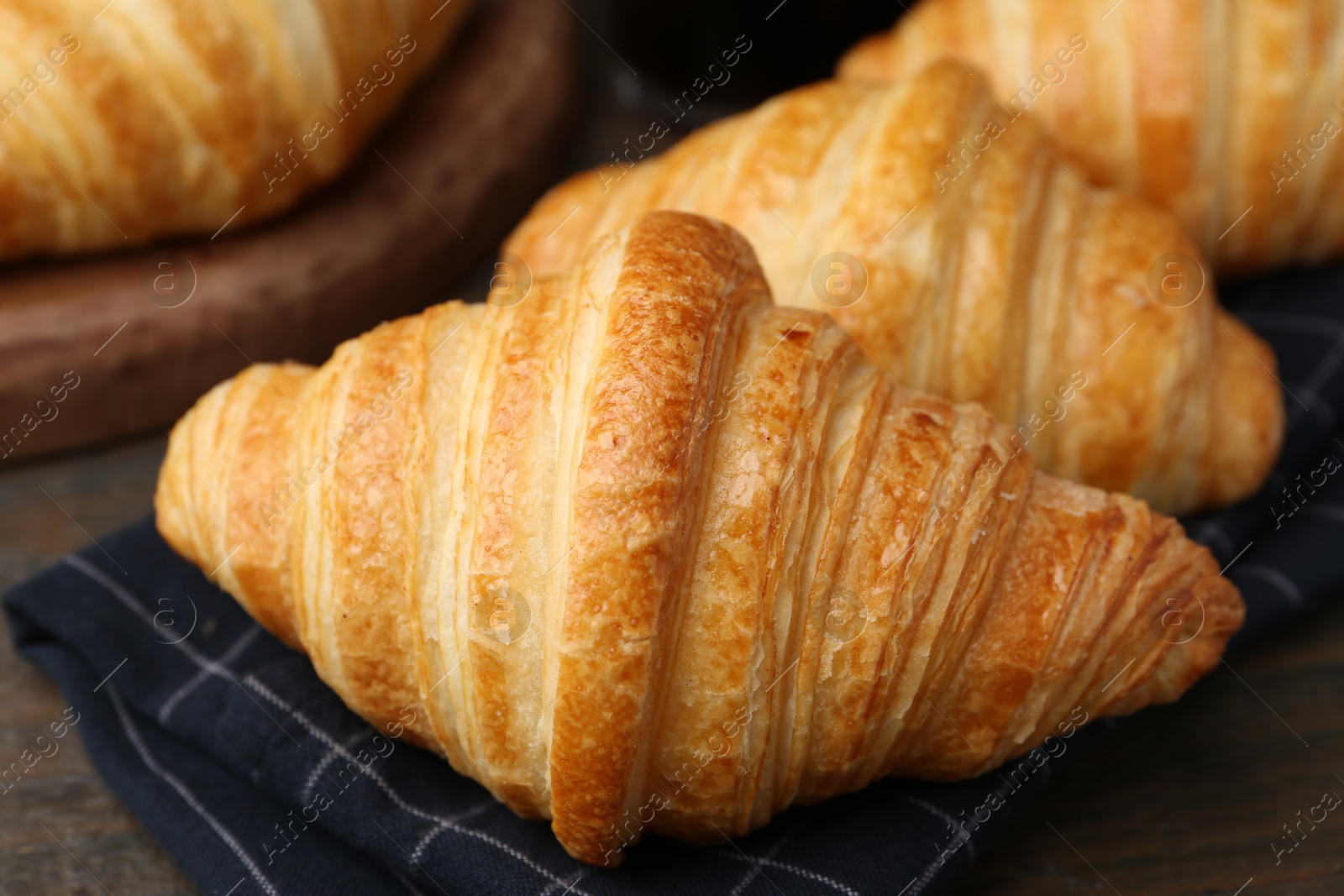 Photo of Tasty fresh croissants on wooden table, closeup. Puff pastry