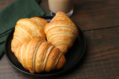 Photo of Tasty fresh croissants on wooden table, closeup. Space for text