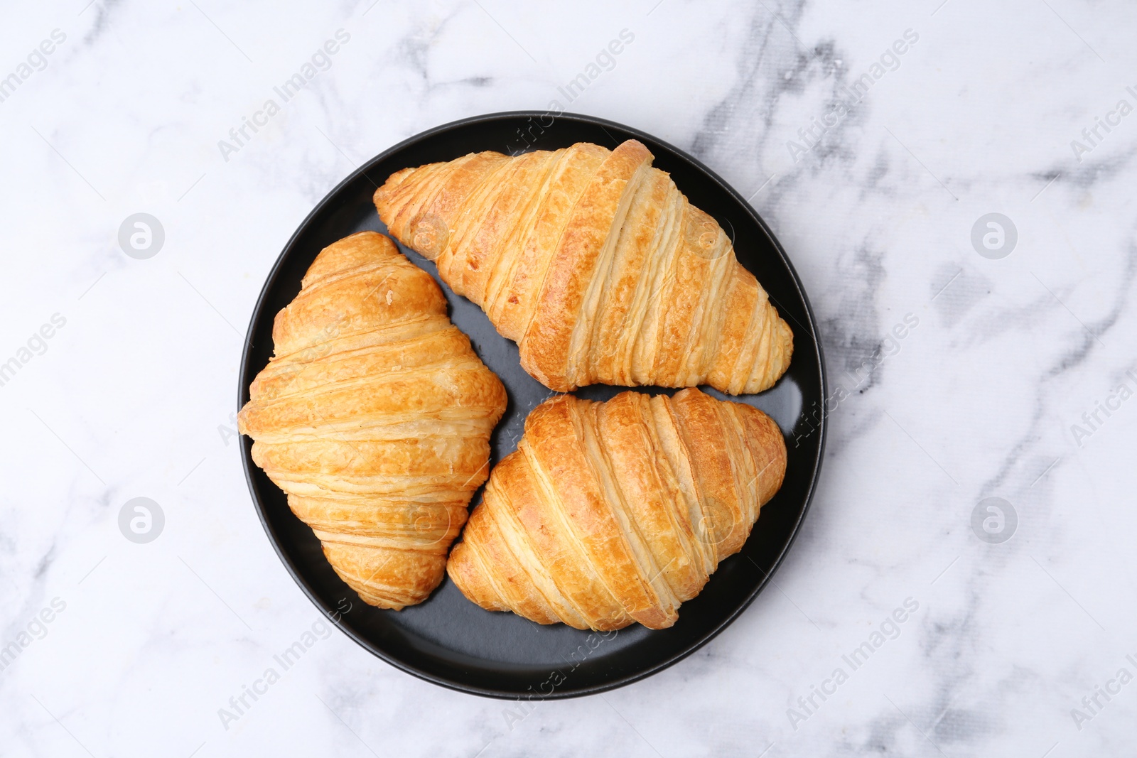 Photo of Tasty fresh croissants on white marble table, top view. Puff pastry