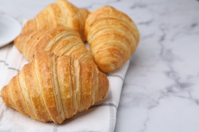 Photo of Tasty fresh croissants on white marble table, closeup. Space for text