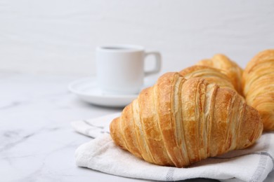 Photo of Tasty fresh croissants and cup of drink on white marble table, closeup. Space for text