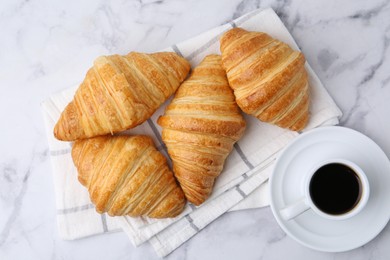 Photo of Tasty fresh croissants and cup of coffee on white marble table, flat lay