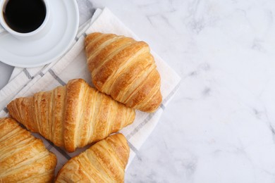 Photo of Tasty fresh croissants and cup of coffee on white marble table, flat lay. Space for text