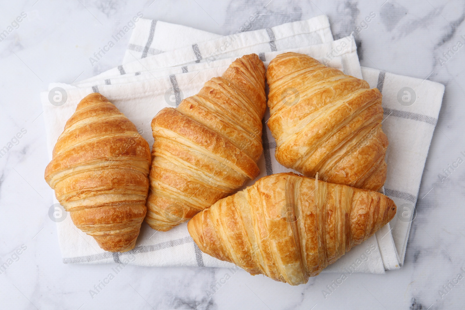 Photo of Tasty fresh croissants on white marble table, flat lay. Puff pastry