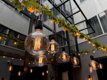 Photo of Light bulbs hanging on cords at outdoor terrace, low angle view