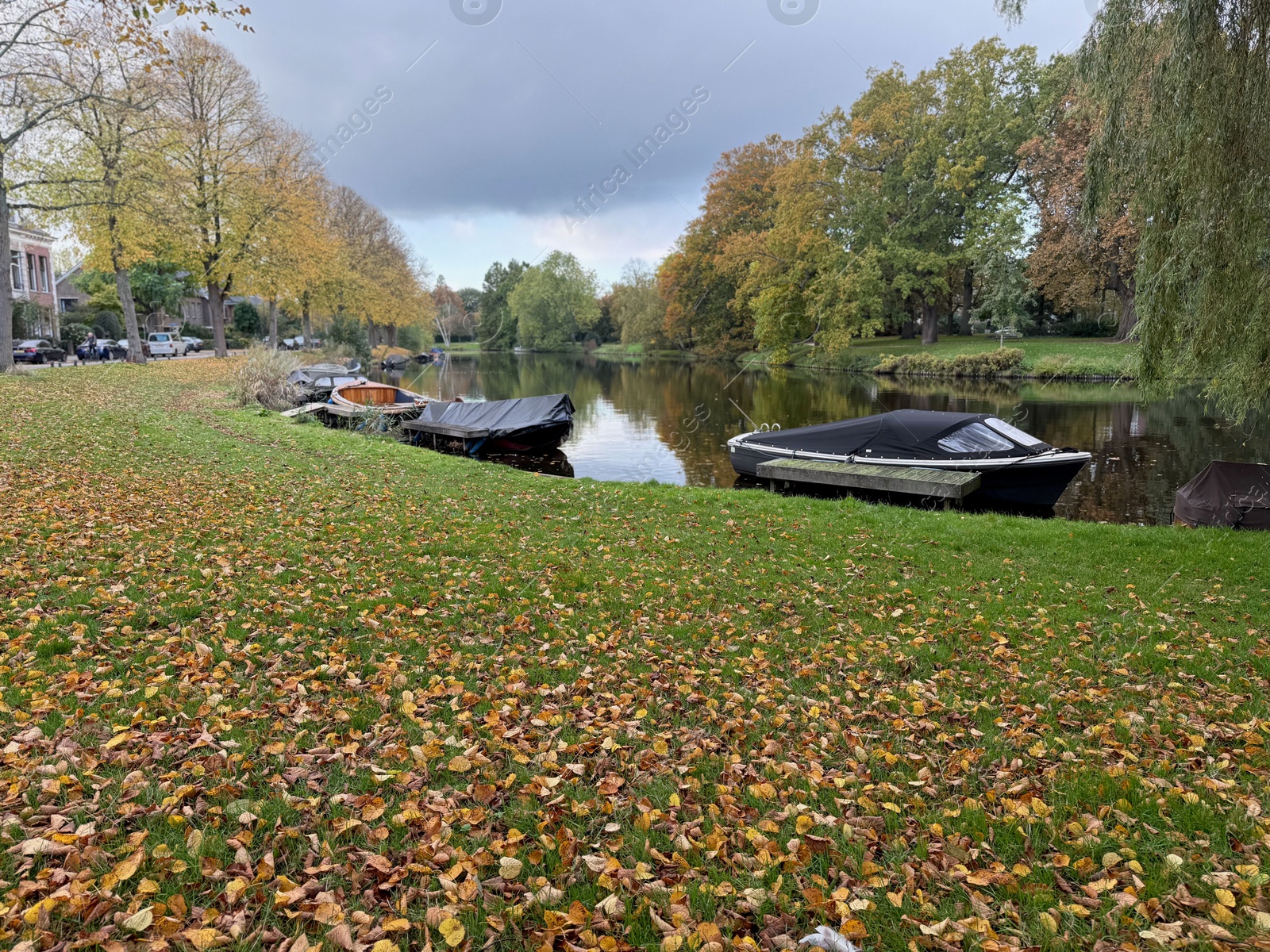 Photo of Beautiful view of canal with moored boats and colorful fallen leaves on autumn day