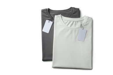 Image of White and grey t-shirts with tags on white background, top view. Mockup for design