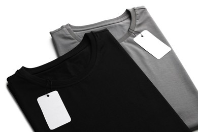 Image of Black and grey t-shirts with tags on white background. Mockup for design