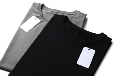 Image of Black and grey t-shirts with tags on white background. Mockup for design