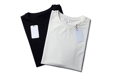 Image of Black and white t-shirts with tags on white background, top view. Mockup for design