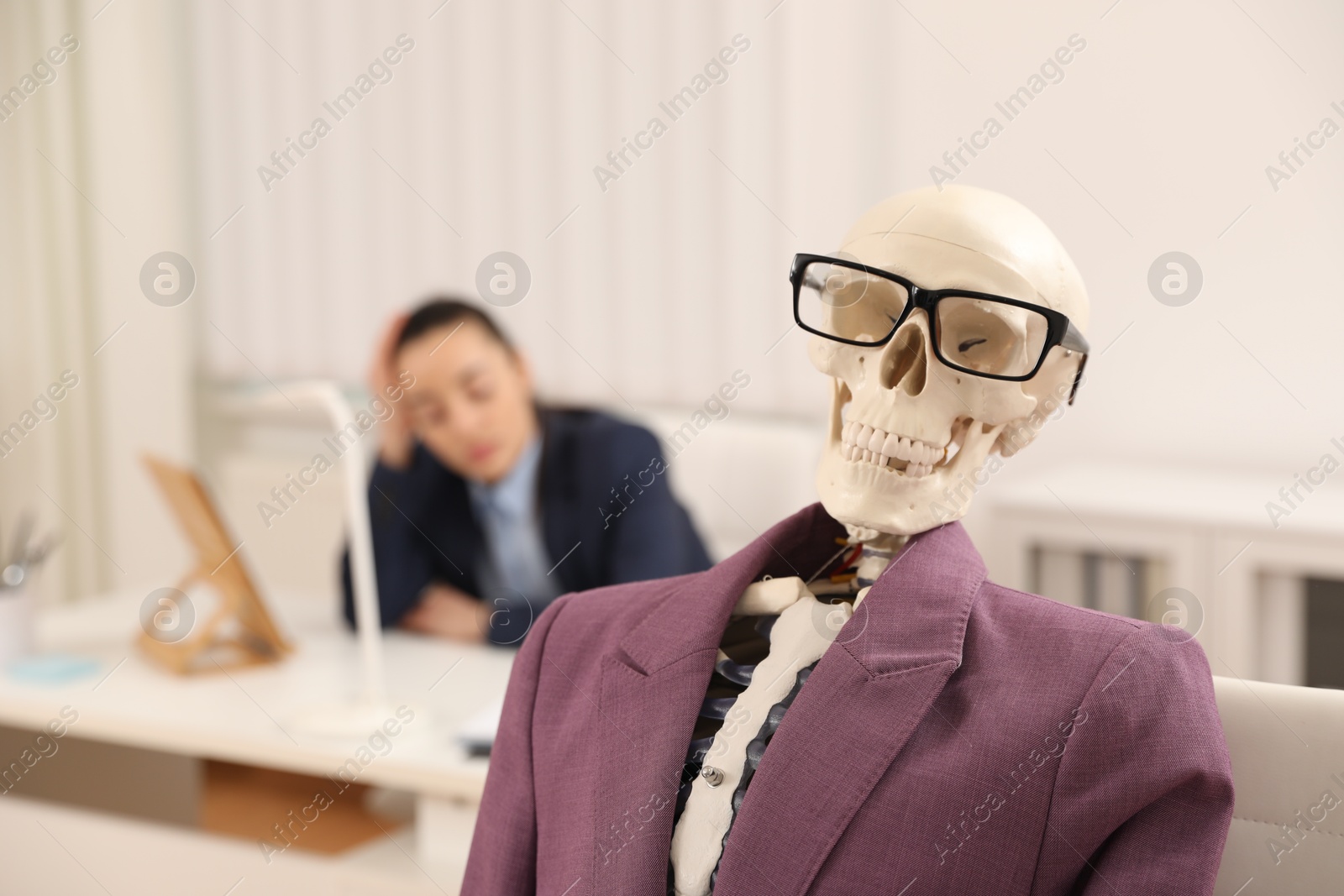 Photo of Human skeleton with suit and glasses in office