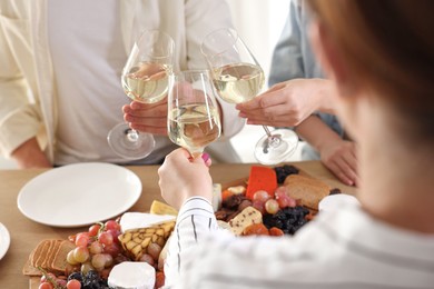 Photo of People clinking glasses of wine at served table, closeup