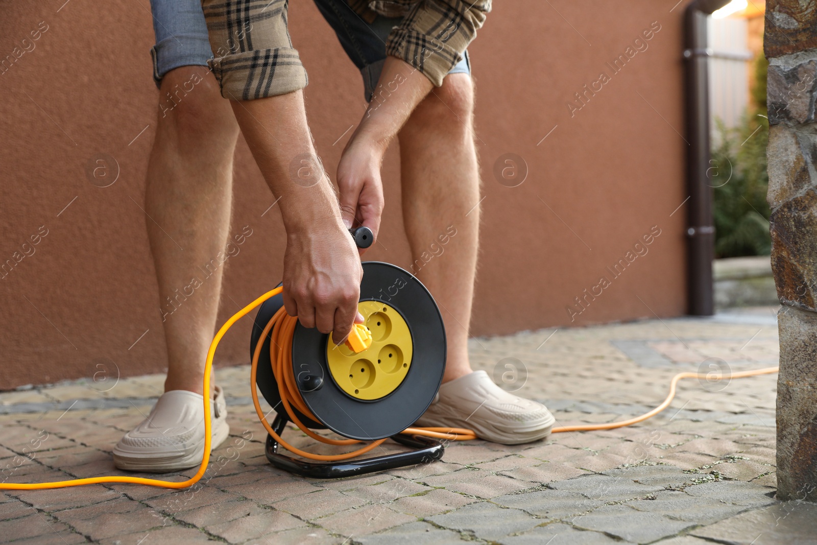 Photo of Man with extension cord reel outdoors, closeup