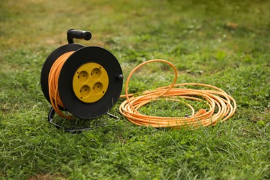 Photo of Extension cord reel on green grass outdoors