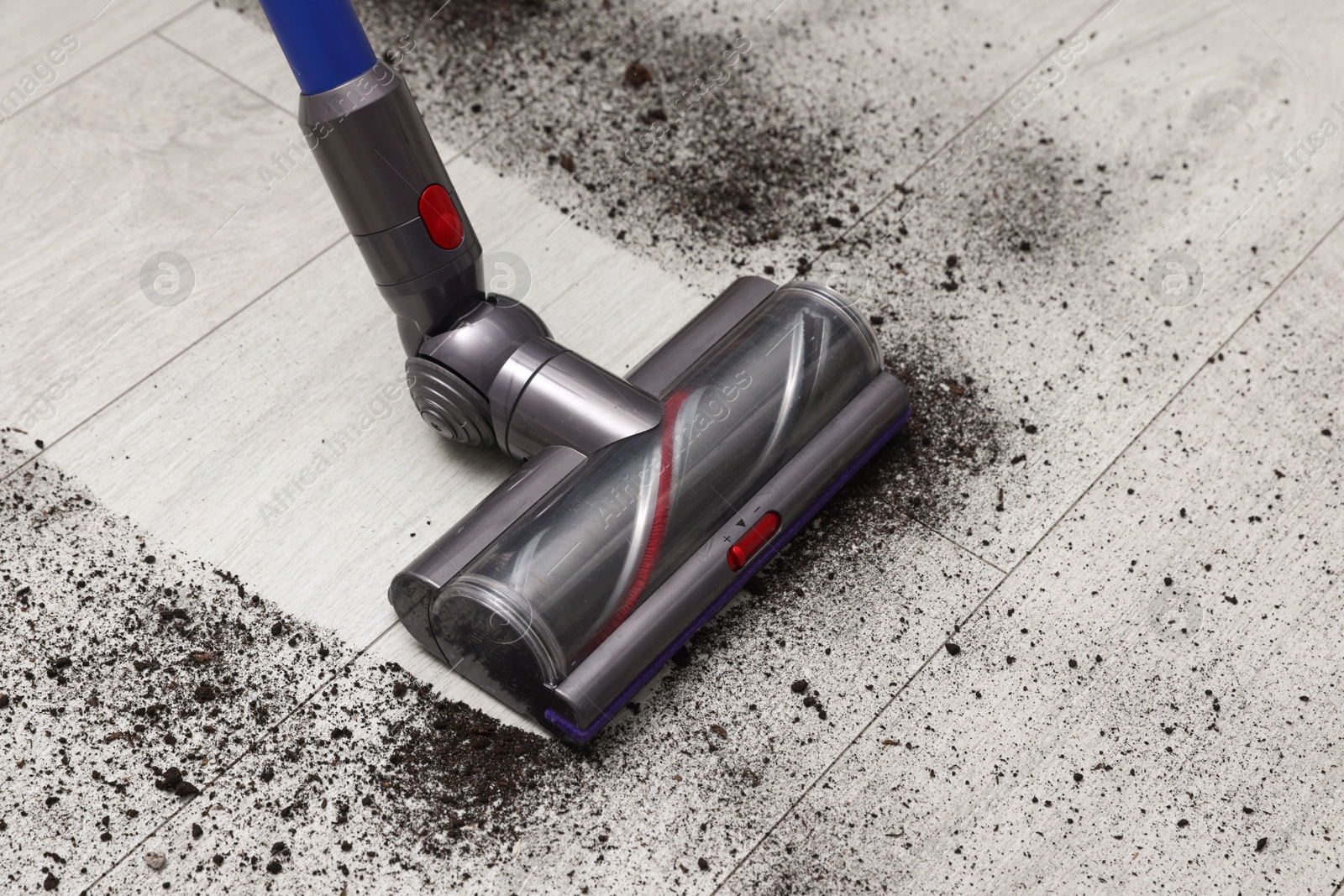 Photo of Cleaning floor with cordless vacuum cleaner indoors, closeup