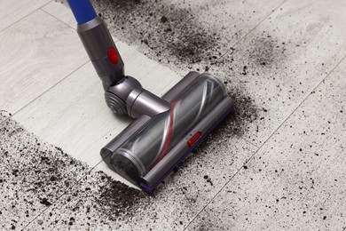 Photo of Cleaning floor with cordless vacuum cleaner indoors, closeup