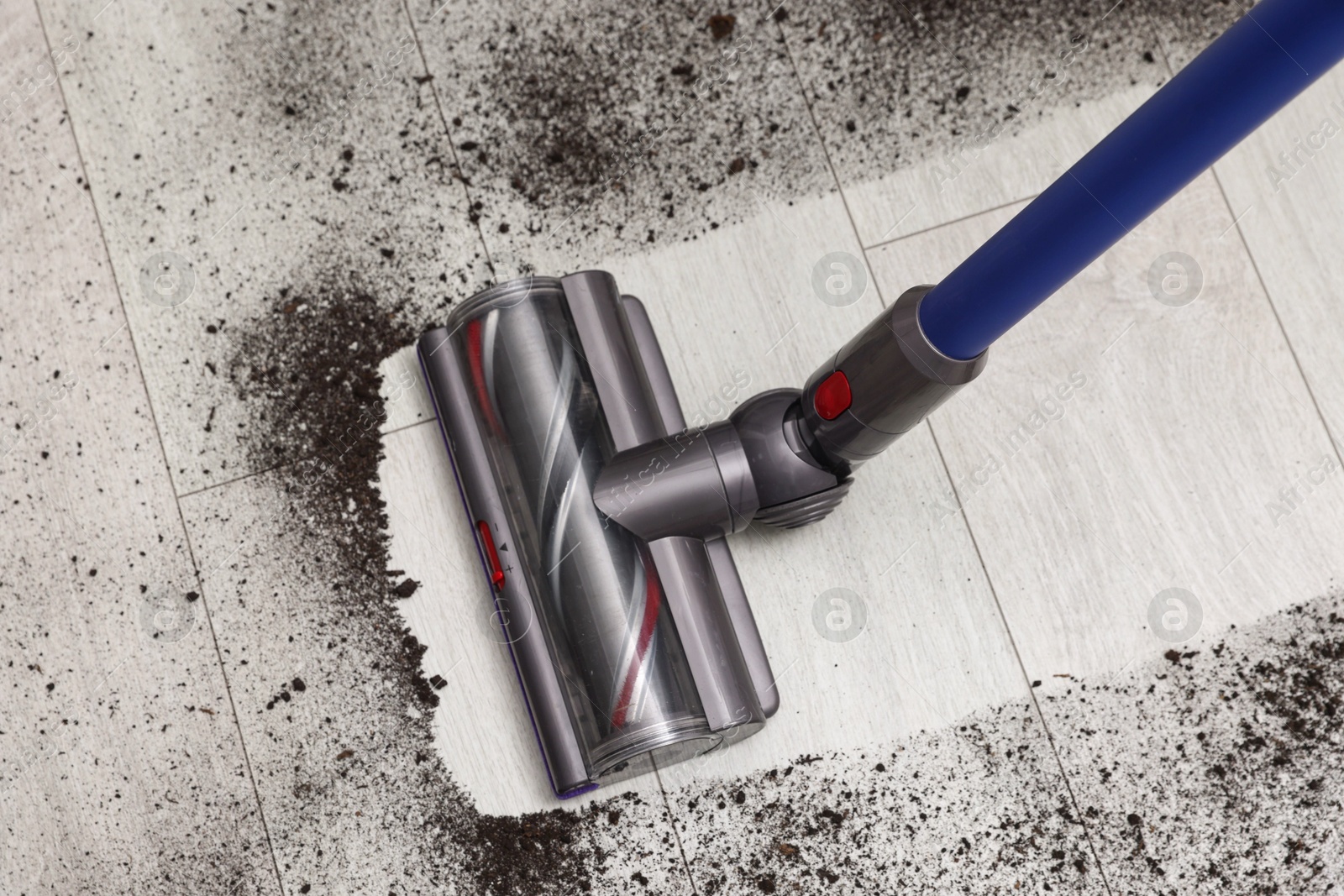 Photo of Cleaning floor with cordless vacuum cleaner indoors, above view