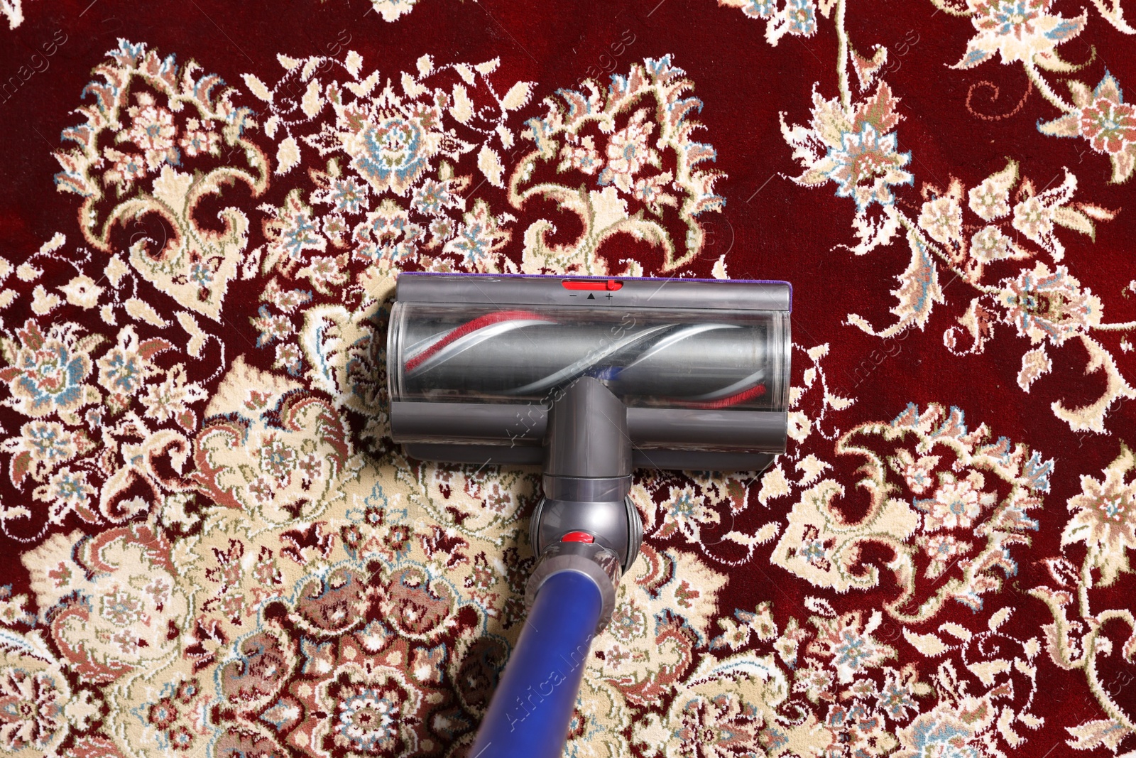 Photo of Cleaning carpet with cordless vacuum cleaner indoors, top view