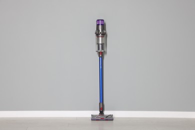 Photo of One cordless vacuum cleaner near grey wall indoors