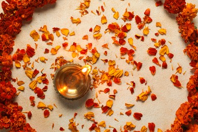 Photo of Diwali celebration. Diya lamp and beautiful flowers on light background, top view