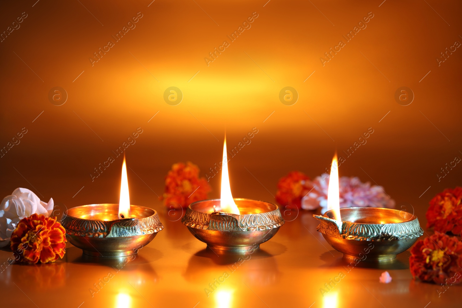 Photo of Diwali celebration. Diya lamps and beautiful flowers on golden background