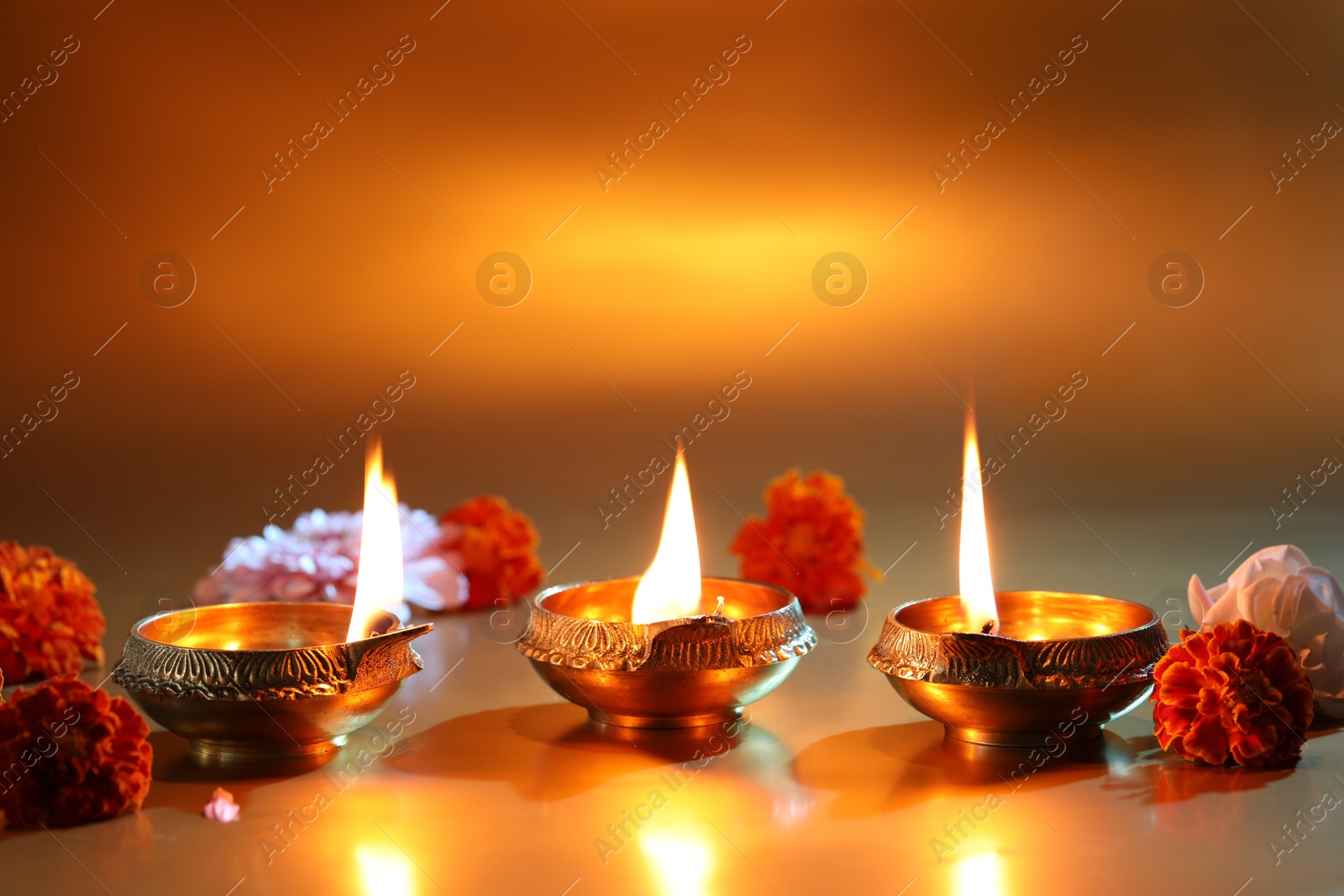 Photo of Diwali celebration. Diya lamps and beautiful flowers on golden background