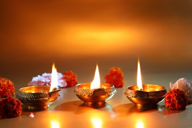 Photo of Diwali celebration. Diya lamps and beautiful flowers on golden background