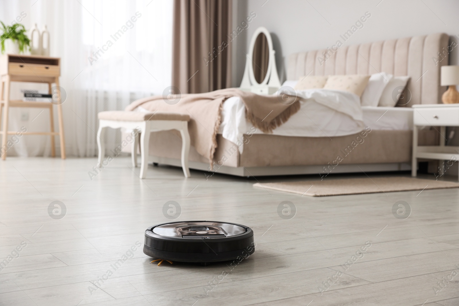 Photo of Robotic vacuum cleaner on wooden floor in bedroom