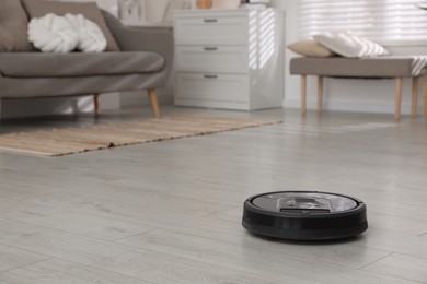 Photo of Robotic vacuum cleaner on wooden floor in room, space for text