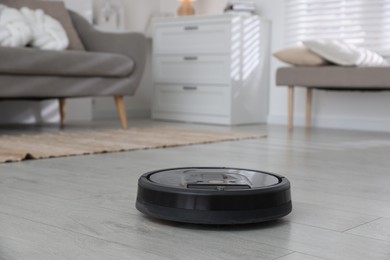 Photo of Robotic vacuum cleaner on wooden floor in living room