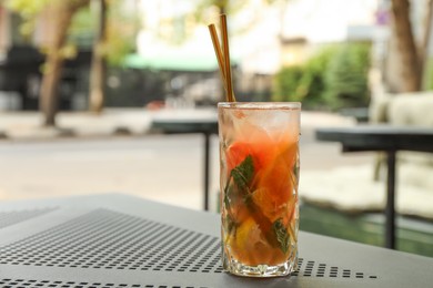 Photo of Glass of tasty refreshing drink and straws on table